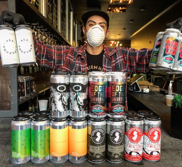 A bartender at Harlem Hops shows off a selection of beers the bar is now selling to-go.